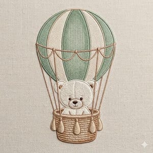 May include: An embroidered patch featuring a white teddy bear sitting in a tan woven basket attached to a hot air balloon. The balloon has alternating sage green and cream vertical panels with tan ropes connecting the basket to the balloon.