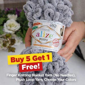 May include: A bundle of gray Alize Puffy finger knitting blanket yarn. The yarn is a plush loop yarn, and the label says "No Needles No Hooks Collection." A banner reads "Buy 5 Get 1 Free!" and the text "Choose Your Colors" is visible.