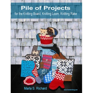 Op de afbeelding: Boekomslag getiteld "Pile of Projects" met diverse gebreide items. De omslag toont een rode mand met teddyberen, wanten en andere kleine projecten. De achtergrond is een gestructureerd, grijs en blauw patroon.