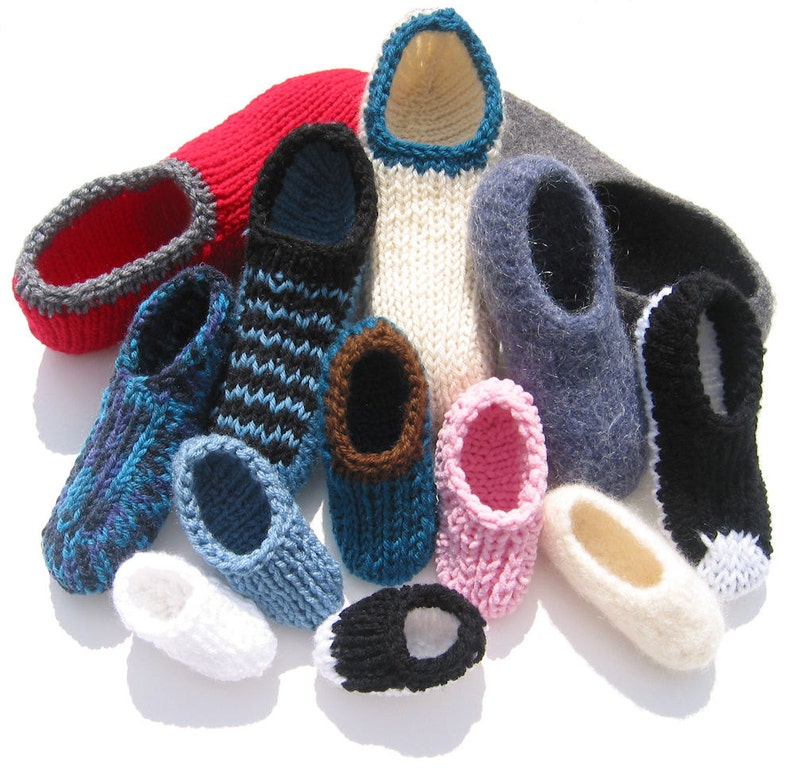 Op de afbeelding: Een verzameling gebreide pantoffels in verschillende kleuren, waaronder rood, blauw, zwart en wit. De pantoffels hebben verschillende patronen en afwerkingsdetails, die een handgemaakte uitstraling laten zien. Sommige hebben gestreepte of getextureerde ontwerpen.