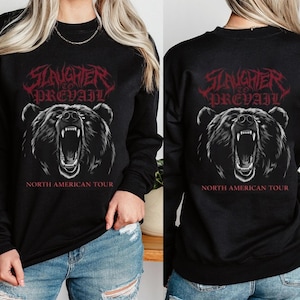 Könnte beinhalten: Schwarzes Langarm-Sweatshirt mit einem brüllenden Bärengrafik. Der Text "Slaughter to Prevail" steht in Rot über dem Bären und "North American Tour" darunter. Die Bärengrafik ist in Schwarz und Weiß.