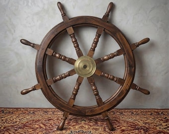 May include: A dark brown wooden ship wheel featuring eight spokes and a central circular brass hub. The wheel has a smooth, polished finish and is constructed with segmented wooden arcs, showcasing the natural grain of the wood throughout.