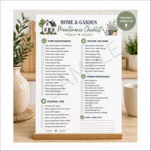 May include: A white Home & Garden Maintenance Checklist printed on paper, displayed on a wooden stand. The document features sections for Home Maintenance, Outside the Home, Garden Maintenance, and Seasonal Jobs, with checkboxes for each task.