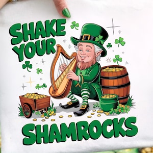Puede incluir: Tela cuadrada blanca con un diseño del Día de San Patricio. El diseño presenta un duende verde tocando un arpa, rodeado de tréboles, monedas de oro y el texto "SHAKE YOUR SHAMROCKS" en verde.