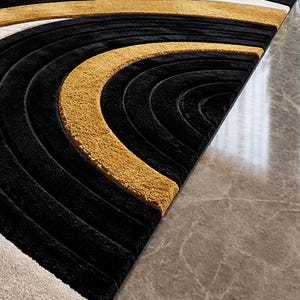 Pode incluir: Um tapete de pel&uacute;cia com um padr&atilde;o geom&eacute;trico de semic&iacute;rculos conc&ecirc;ntricos em cores alternadas preto e amarelo mostarda. O tapete tem uma textura de pelo alto e baixo que cria sulcos profundos e cristas elevadas no design curvo.