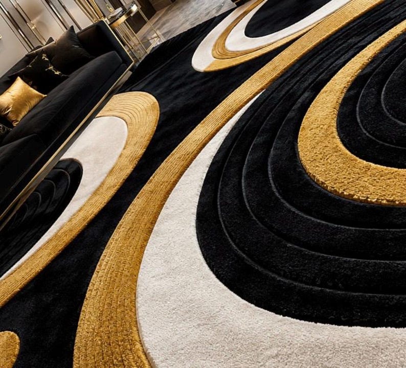 Pode incluir: Um tapete grande com um padr&atilde;o repetitivo de formas ovais conc&ecirc;ntricas em preto, branco e dourado. O design consiste em faixas texturizadas e elevadas de pelo dourado e preto que se alternam com sec&ccedil;&otilde;es brancas lisas e uniformes.