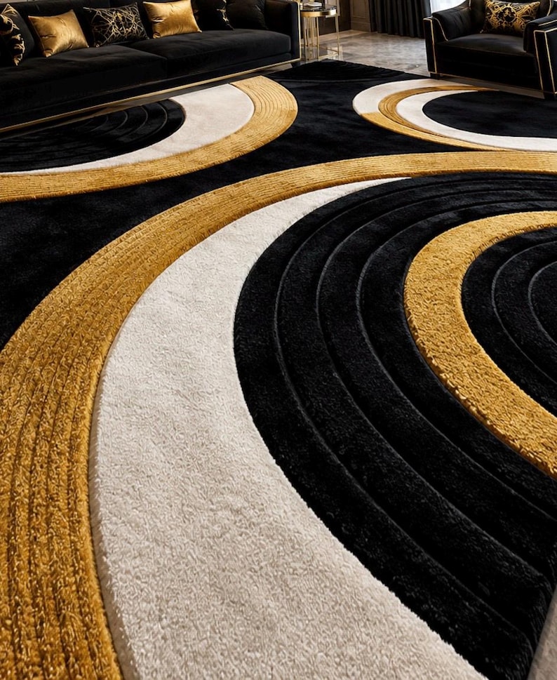 Pode incluir: Um tapete grande com um padr&atilde;o geom&eacute;trico arrojado de c&iacute;rculos conc&ecirc;ntricos em preto, branco e dourado. O design consiste em faixas espessas e texturizadas de alturas variadas que criam um efeito tridimensional na superf&iacute;cie.