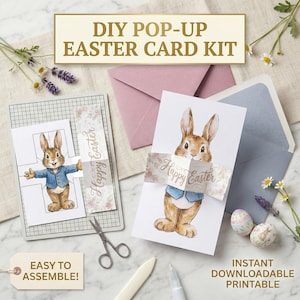 May include: DIY pop-up Easter card kit featuring a watercolor illustration of a bunny wearing a blue jacket. The kit includes cards, envelopes, and decorative elements. Text on the card reads "Happy Easter" and "Easy to Assemble!" and "Instant Downloadable Printable".