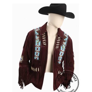 Può includere: Giacca in camoscio bordeaux con frange e dettagli di perline. La giacca presenta un cappello da cowboy nero ed è decorata con perline turchesi e bianche e disegni di aquile. La giacca ha lunghe frange lungo le maniche e l'orlo inferiore.
