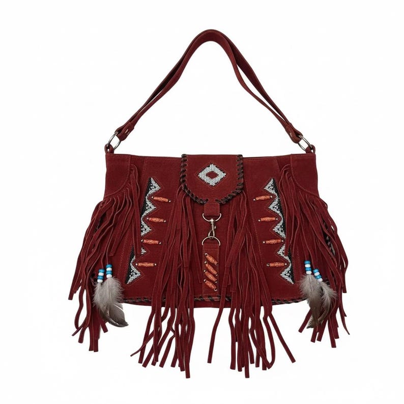 May include: A burgundy suede shoulder bag with long fringe and decorative beading. The bag features a flap with a diamond pattern and a long strap. Small feathers and blue beads dangle from the fringe.