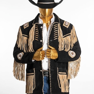 May include: A black suede jacket with tan fringe and decorative stitching, paired with a black cowboy hat. The jacket features intricate detailing on the shoulders and sleeves, and is worn over a white shirt and blue jeans.