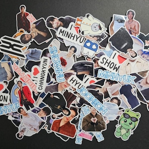 May include: A collection of various stickers featuring images of people, cartoon characters, and text. The stickers are in various shapes and sizes, with a mix of colors and designs. Some stickers include the names "MINHYUK", "JOOHEON", "KIHYUN", "SHOWNU", and "CHANGKYUN".