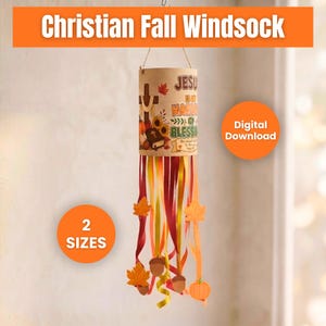 May include: A cylindrical windsock featuring a tan body with the text Jesus is my harvest of blessings, a cross, and autumn motifs. It has long, hanging ribbons in shades of orange, yellow, and red, accented with paper leaf and pumpkin cutouts.