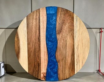 Handcrafted acacia wood cutting board with resin detailing, featuring a round serving board design