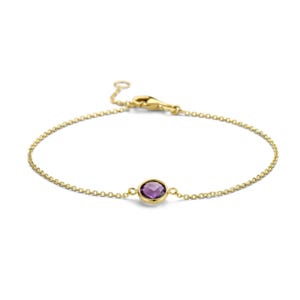 May include: A delicate gold chain bracelet featuring a single round, faceted purple amethyst gemstone set in a gold bezel. The bracelet includes a thin cable chain and a secure lobster claw clasp mechanism for fastening around the wrist.