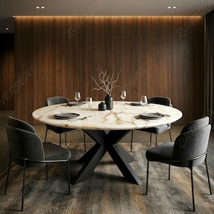 May include: A round dining table with a white marble top featuring brown veining and a black X-shaped metal base. Four dark gray upholstered chairs with thin black metal legs are arranged around the table, which is set with plates and glasses.