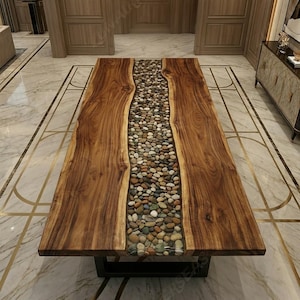 May include: A large, rectangular wooden table with a river of smooth, multicolored stones running down the center. The table has a dark brown finish and sits on a black metal base. The table is approximately 96 inches long and 40 inches wide.