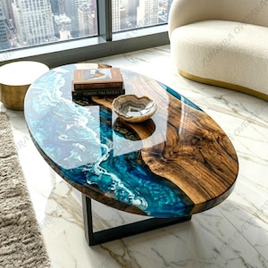May include: An oval coffee table featuring a natural wood slab with a prominent grain pattern and a glossy blue resin inlay that mimics ocean waves with white foam details. A small, circular, banded stone bowl sits on the table surface.