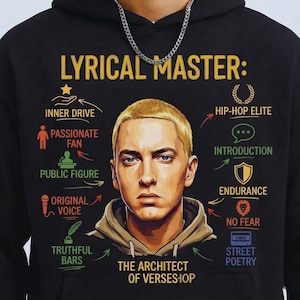 May include: Black hoodie featuring a portrait of a blonde man with blue eyes, surrounded by text and graphics. The text includes "LYRICAL MASTER" and phrases like "INNER DRIVE," "HIP-HOP ELITE," and "THE ARCHITECT OF VERSES." A silver chain is visible at the top.