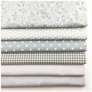 May include: A stack of fabric samples in various patterns. The fabrics include floral, polka dot, star, gingham, striped, and dotted designs. The color palette is primarily gray and white, creating a soft and neutral aesthetic.