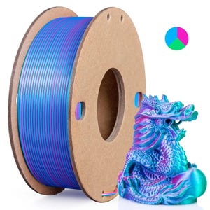 May include: A spool of blue, pink, and purple 3D printing filament next to a colorful dragon figurine. The filament is on a cardboard spool. The dragon is a vibrant mix of blues, purples, and greens.