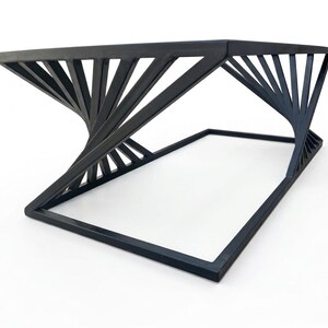 May include: A black metal coffee table featuring a rectangular top and a base connected by angled, radiating support struts that create a twisted, fan-like geometric pattern between the upper frame and the lower rectangular floor support.
