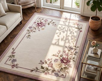May include: Cream-coloured rectangular rug featuring a floral pattern in shades of purple, pink, and green. The rug has a purple border. The rug is placed on a dark wood floor. The rug's dimensions are approximately 200cm x 300cm.