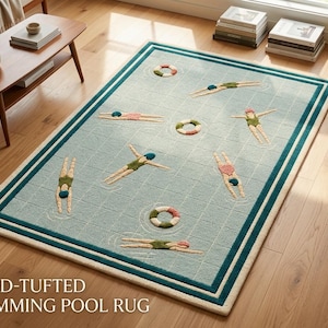 May include: A rectangular area rug featuring a light blue grid pattern resembling a swimming pool. The rug includes tufted designs of swimmers in various poses and colourful life preservers, bordered by a dark teal and cream frame.