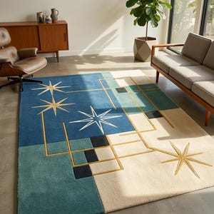 May include: A rectangular area rug featuring a geometric pattern in blue, teal, cream, and black. The design includes gold-coloured starburst motifs and linear grid lines. A small white tag at the corner displays the text Modern Mid-Century.