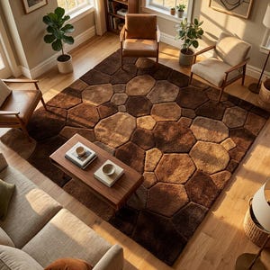 Op de afbeelding: Een groot, bruin vloerkleed met een uniek, steenachtig patroon. Het vloerkleed heeft verschillende bruintinten, waardoor een gestructureerd, geometrisch ontwerp ontstaat. Het vloerkleed is geplaatst in een woonkamer met houten meubels en hardhouten vloeren.