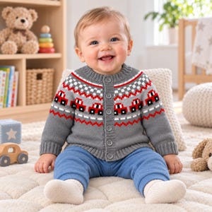 May include: A grey long-sleeve knit cardigan featuring a repeating pattern of small red cars across the chest and shoulders, finished with a ribbed crew neckline, ribbed cuffs, and a vertical row of five matching grey buttons down the front centre.
