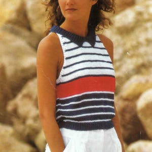 Puede incluir: Un top sin mangas a rayas con cuello azul marino y una franja roja. El top se combina con pantalones blancos. El top tiene rayas horizontales blancas y azul marino. El atuendo es adecuado para climas cálidos.