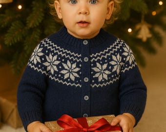 Puede incluir: Una chaqueta de punto azul marino con un patrón de copos de nieve blancos en el pecho y los hombros, con cierre de botones. La prenda se combina con pantalones vaqueros azules y se sostiene junto a una caja de regalo marrón con lazo rojo.