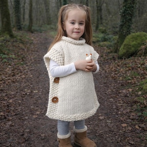 May include: A white ceramic mug with a black handle and the text "But First, Coffee" in a bold, black font. The mug is set against a blurred background, suggesting a cozy setting. The mug appears to be approximately 4 inches tall.