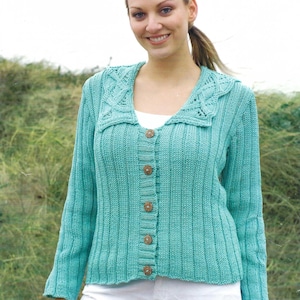 Könnte beinhalten: Türkisgrüne Strickjacke mit Rippenmuster, dekorativem Kragen und Holzknöpfen. Der langärmlige Pullover wird mit einer weißen Hose kombiniert. Die Länge der Strickjacke beträgt ca. 61 cm.