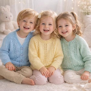 Puede incluir: Tres niños sonriendo, vistiendo jerséis de punto en colores pastel. Un niño lleva una rebeca azul claro sobre una camiseta blanca, mientras que las niñas llevan jerséis amarillos y verde menta. Están sentados sobre una superficie blanca texturizada.