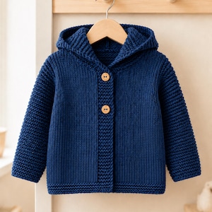 Könnte beinhalten: Eine dunkelblaue Strickjacke mit Kapuze, die durchgehend mit einem strukturierten Kraus-rechts-Muster gestrickt ist. Das Kleidungsstück verfügt über eine Kapuze, lange Ärmel und einen Vorderverschluss mit zwei hellbraunen Holzknöpfen.
