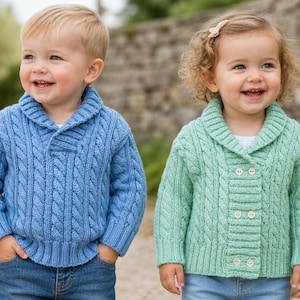 Op de afbeelding: Twee lachende kinderen in kabelgebreide truien. Eén kind draagt een lichtblauwe trui met een sjaalkraag en een knoopsluiting. Het andere kind draagt een mintgroene trui met een sjaalkraag en een knoopsluiting. Beide kinderen dragen een blauwe jeans.