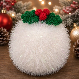 May include: A spherical, white, fuzzy, yarn-based ornament featuring a crocheted holly decoration on top. The holly consists of three small, round, red berries and two green, textured leaves. The white yarn has a subtle, shimmering, iridescent quality.