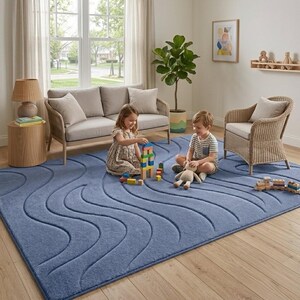 Op de afbeelding: Een groot rechthoekig vloerkleed in een effen, stoffige blauwe kleur met een gestructureerd, uitgesneden golfpatroon over het oppervlak. Het kleed heeft een zachte, dichte pool en bedekt een groot deel van de lichte houten vloer in de kamer.