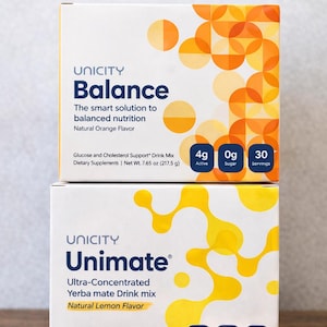 May include: Two boxes of Unicity dietary supplements. The top box is "Balance" with "Natural Orange Flavour" and the bottom box is "Unimate" with "Natural Lemon Flavour". Both boxes have nutritional information and the text "FREE INTERNATIONAL DELIVERY".