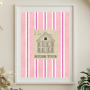 May include: A framed wall art print featuring a vertical pattern of alternating light pink and bright magenta stripes. Centered on the stripes is a beige rectangular block with a black line drawing of a house and the text HOUSE TOUR.