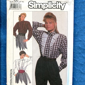 May include: Simplicity sewing pattern 8742. The pattern features illustrations of blouses and a skirt. The main image shows a woman wearing a plaid blouse with a ruffled collar and black pants. The pattern size is NN (10-16).