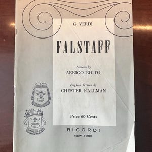 May include: A white ceramic mug with a black handle and the text "But First, Coffee" in a black, bold font. The mug is on a white surface. The mug is approximately 4 inches tall.