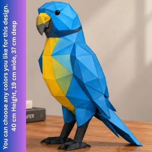 May include: A geometric parrot sculpture featuring a blue head and wings, a yellow chest, and black feet. The text on the side states: You can choose any colors you like for this design. 40 cm Height, 19 cm wide, 37 cm deep.