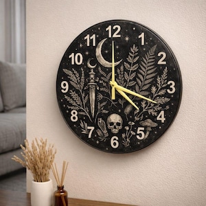 May include: Black round wall clock with a celestial and botanical design. The clock face features a crescent moon, stars, a dagger, skull, and botanical illustrations. The clock hands are yellow.