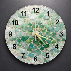 Könnte beinhalten: Runde Wanduhr mit einem Mosaikdesign aus Meeresglas in Grün- und Blautönen. Das Zifferblatt hat schwarze Ziffern und goldfarbene Zeiger. Ein dekorativer Artikel für die Wohnkultur.