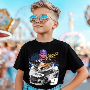 May include: Black t-shirt with a graphic of a race car and four men, with an American flag and the number 9. The shirt is worn by a child wearing mirrored sunglasses.