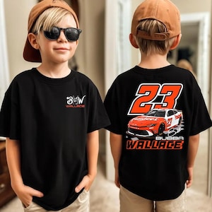 Könnte beinhalten: Ein schwarzes T-Shirt mit einem kleinen weißen Logo auf der Vorderseite mit dem Text BW Wallace. Die Rückseite zeigt eine große orangefarbene Nummer 23, eine Grafik eines orange-weißen Rennwagens und den Text Bubba Wallace in fetter Schrift.