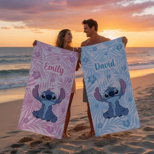 May include: Two beach towels, one pink and one blue, each with a cartoon character and tropical leaf and flower patterns. The pink towel has the name "Emily" and the blue towel has the name "David".